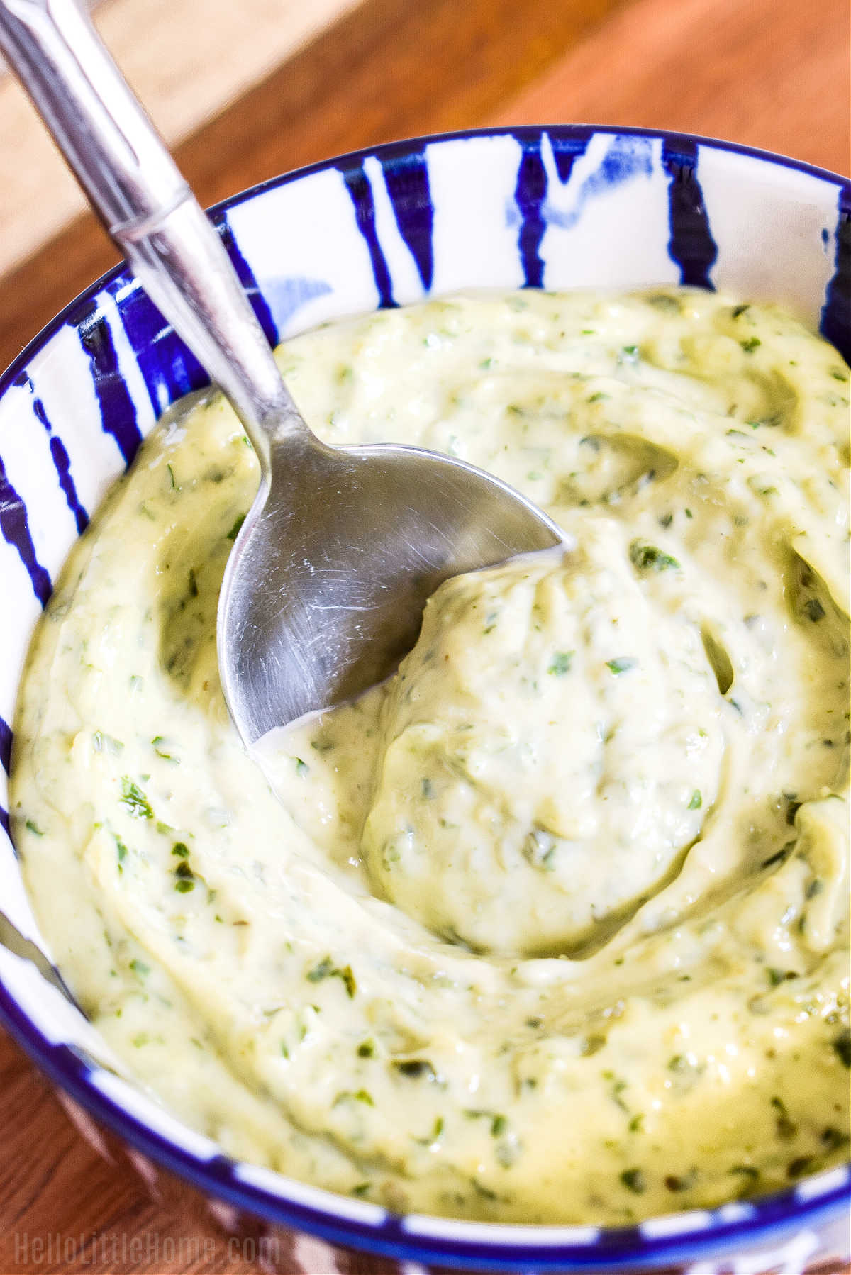 A spoon stirring the finished pesto mayonnaise sauce.