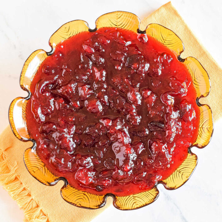 The Cranberry Sauce recipe served in a glass bowl on a marble counter.