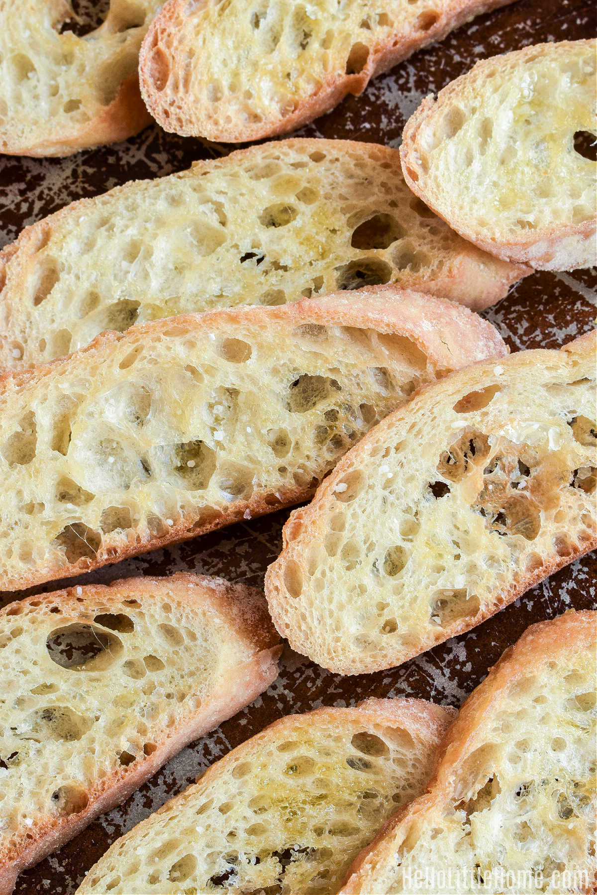 Closeup of toasted baguette slices on a baking sheet.