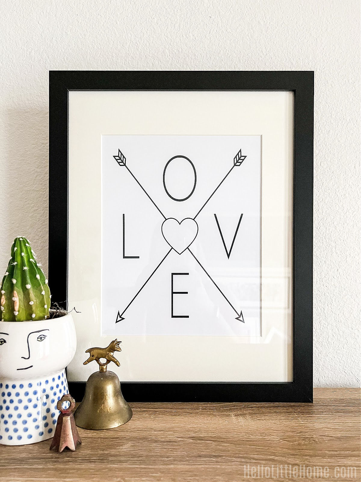The love heart wall art in a black frame on a wood table.