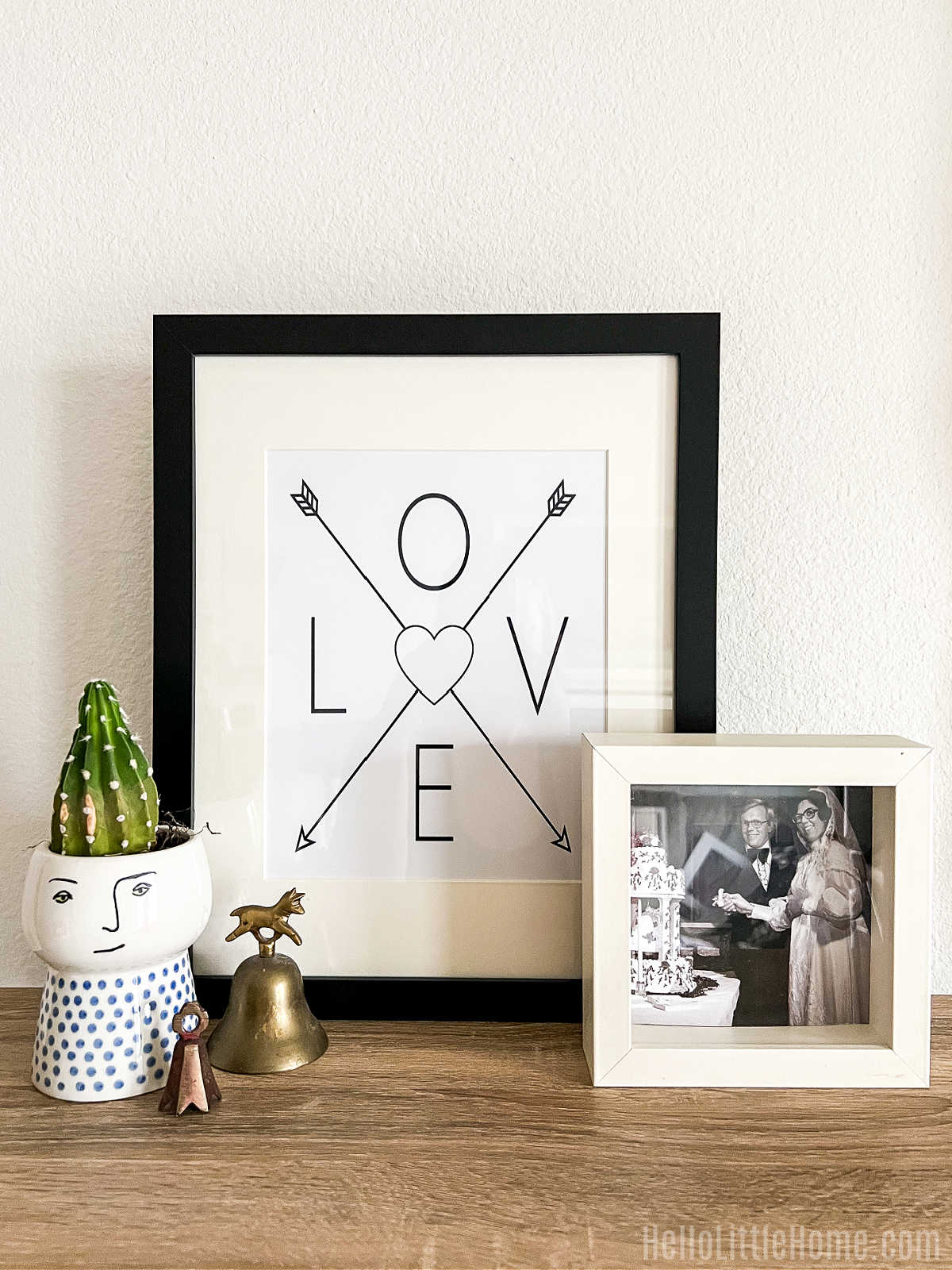 A table topped with the framed love print, photo, and other decor items.