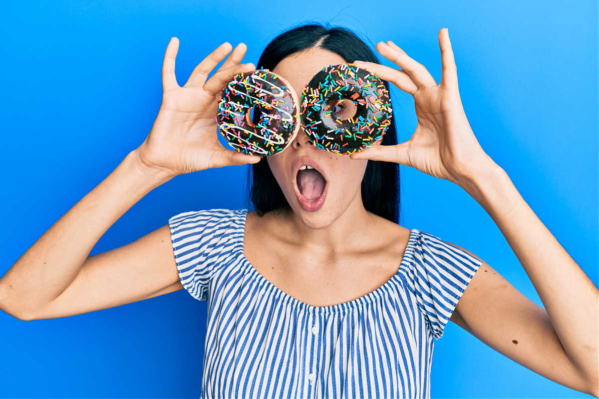 A woman holding two donuts in front of her eyes.