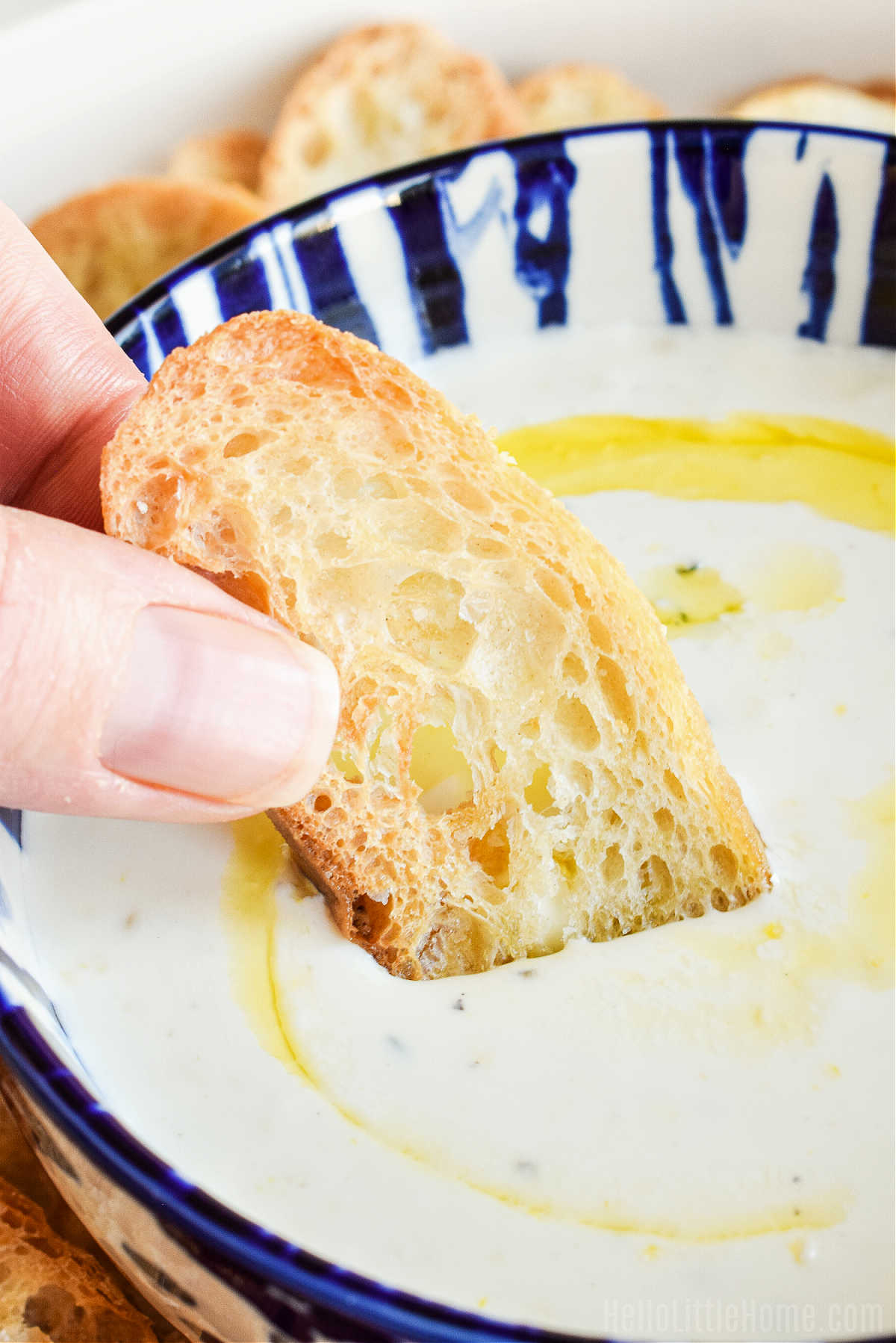 Closeup of a hand dipping bread in the dip.