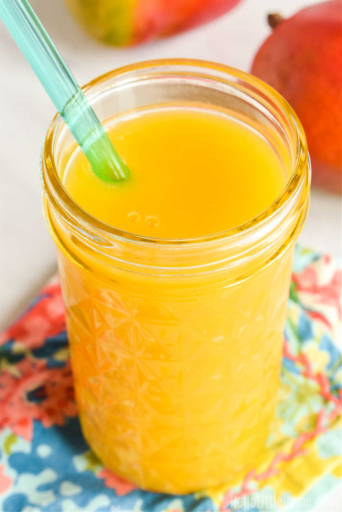 A recipe for mango juice served in a tall glass with a straw.