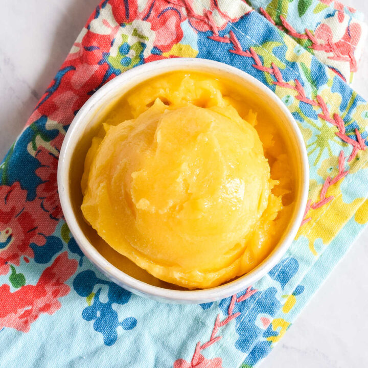 A bowl of Mango Sorbet on a patterned napkin.