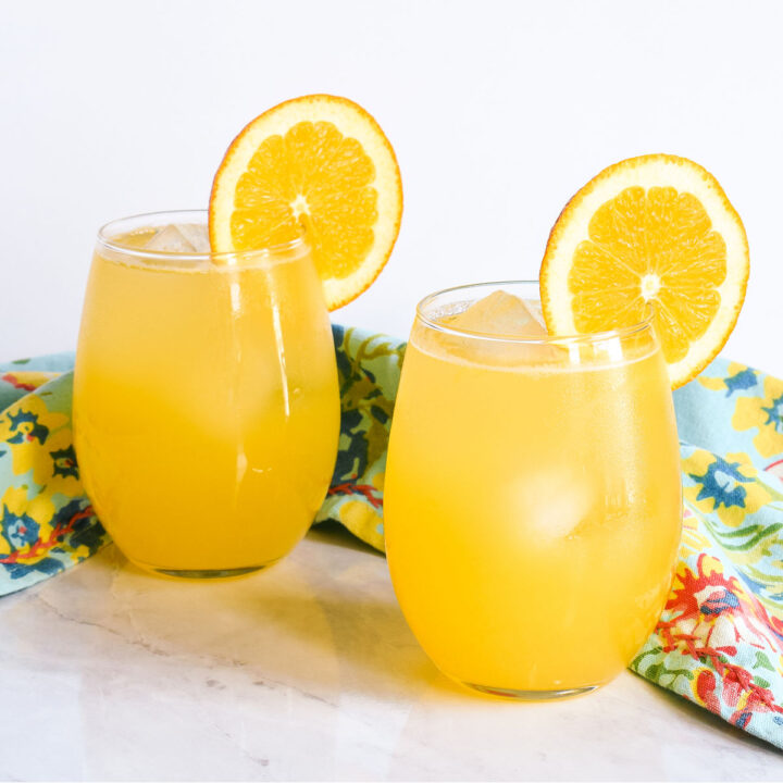 The finished Orangeade served in two glasses on a marble counter.