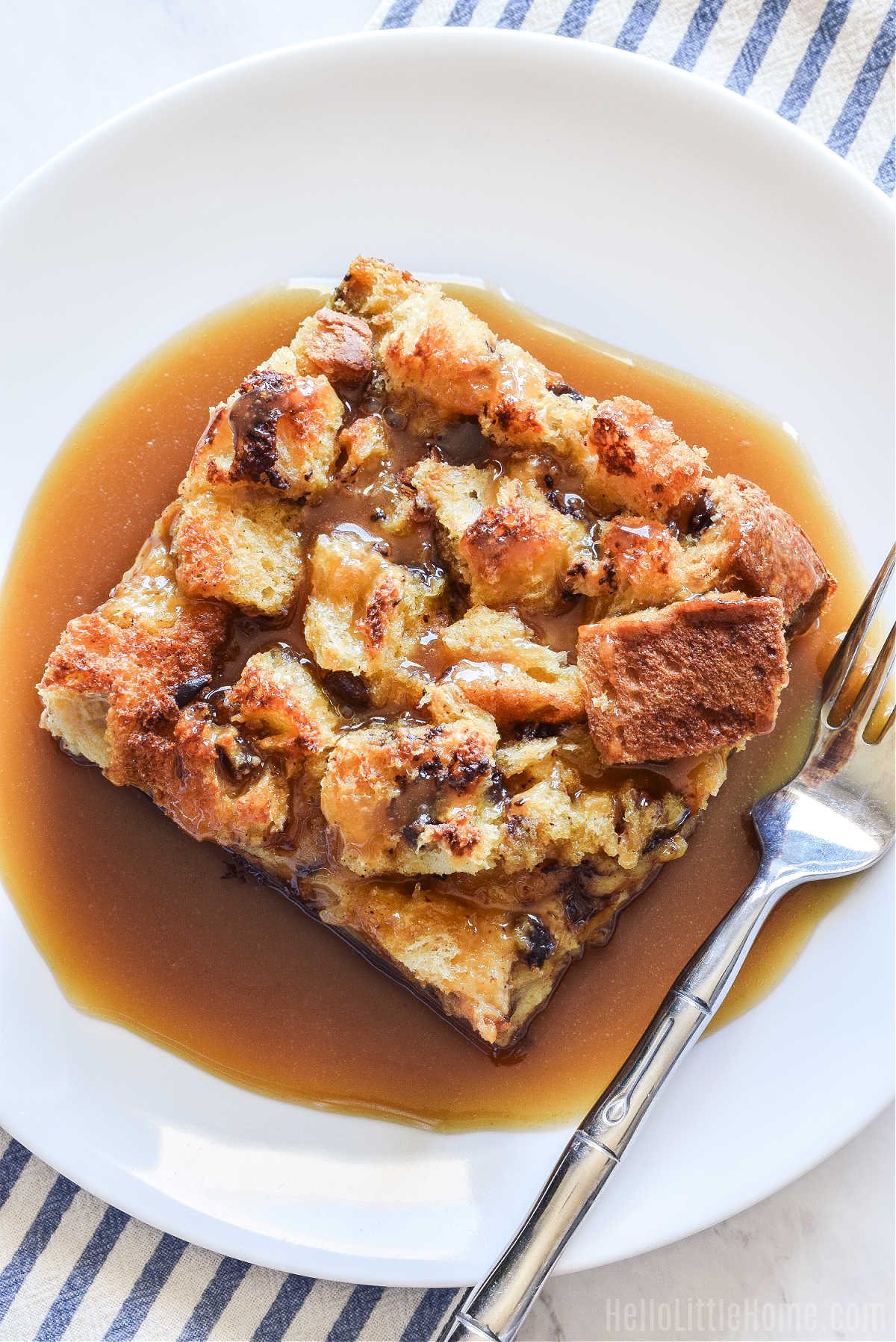 A slice of the Christmas bread pudding served on a white plate with a fork.