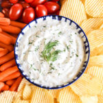 Dill Dip served in a bowl and surrounded by chips and veggies.