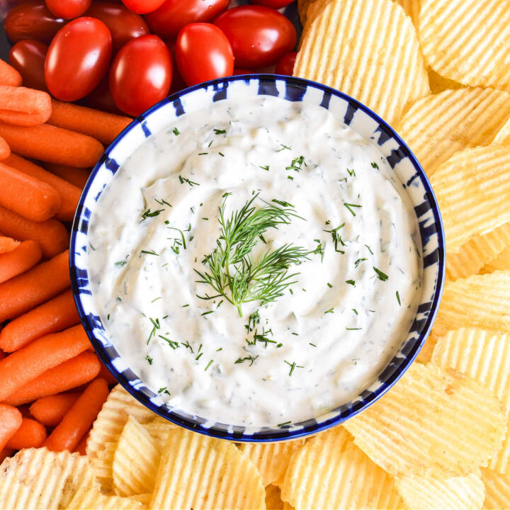 Dill Dip served in a bowl and surrounded by chips and veggies.