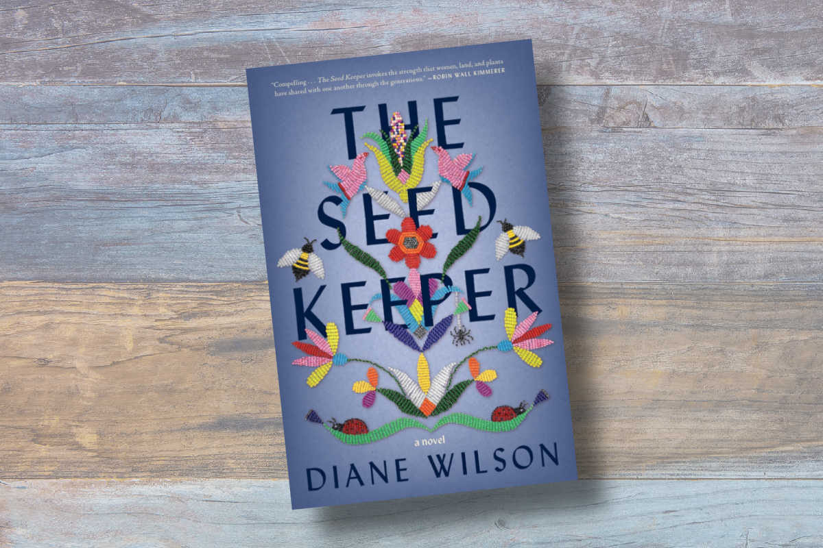 The cover of The Seed Keeper on a colored wood background.