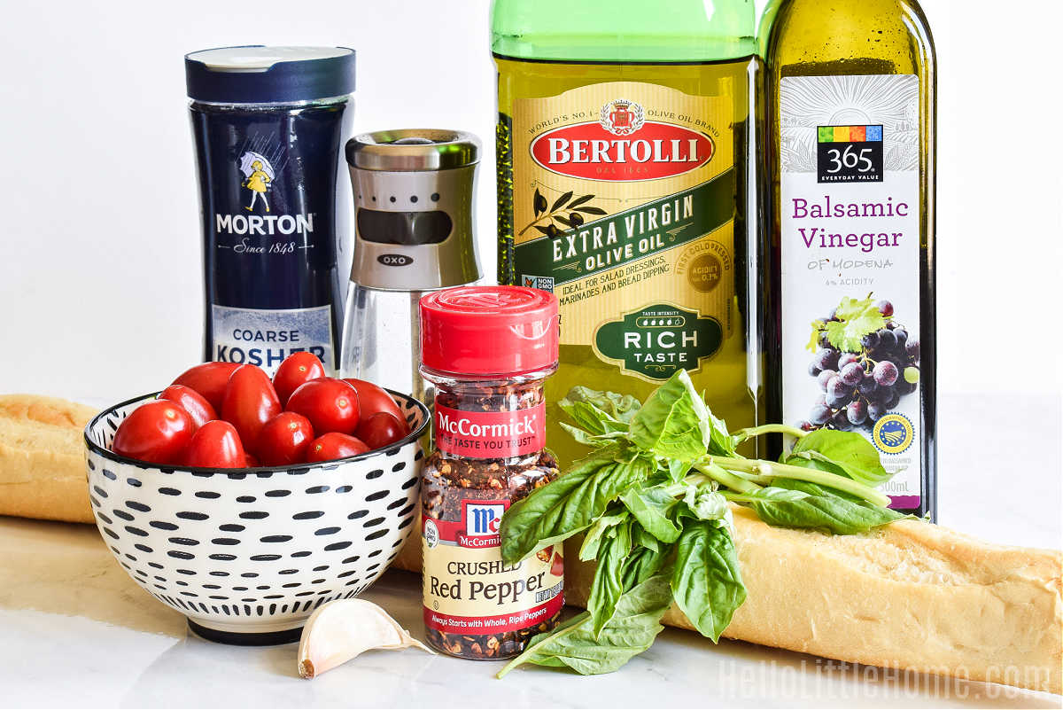 Tomato Crostini ingredients arranged on a white marble counter.