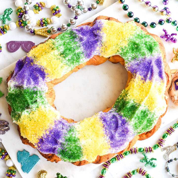 A Cinnamon Roll King Cake served on a white tray and surrounded by beads.