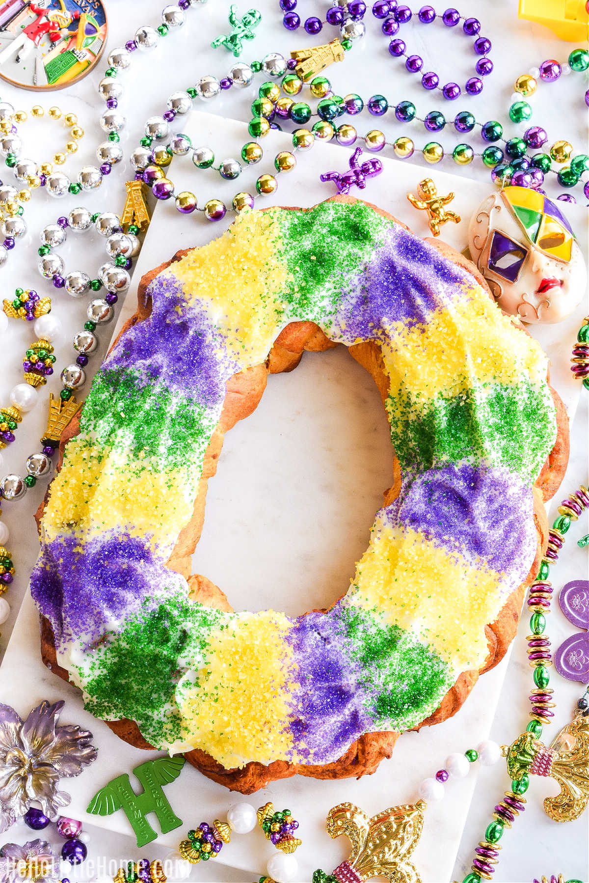 The finished Mardi Gras cake served on a tray surrounded by beads.