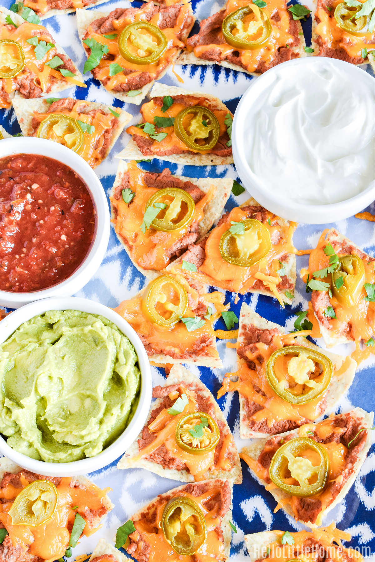 A large tray of the easy nachos recipe served alongside bowls of toppings.