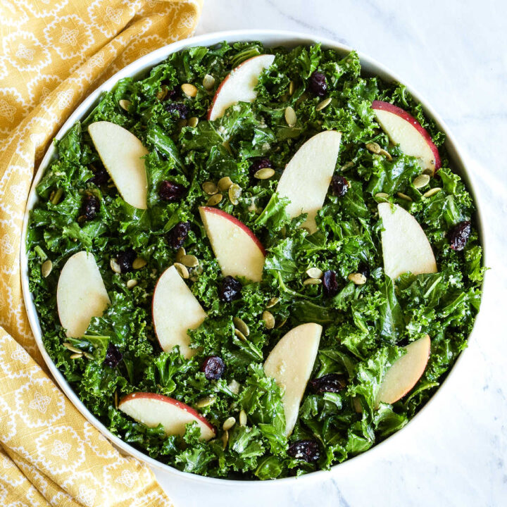 A bowl of Kale Pumpkin Seed Salad served next to a yellow napkin.