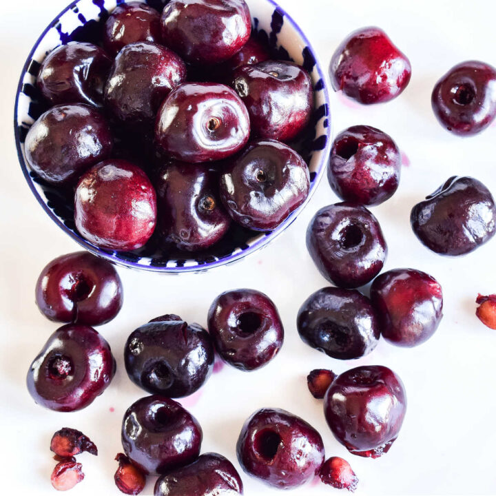 Pitted cherries on a white plate and in a small bowl.