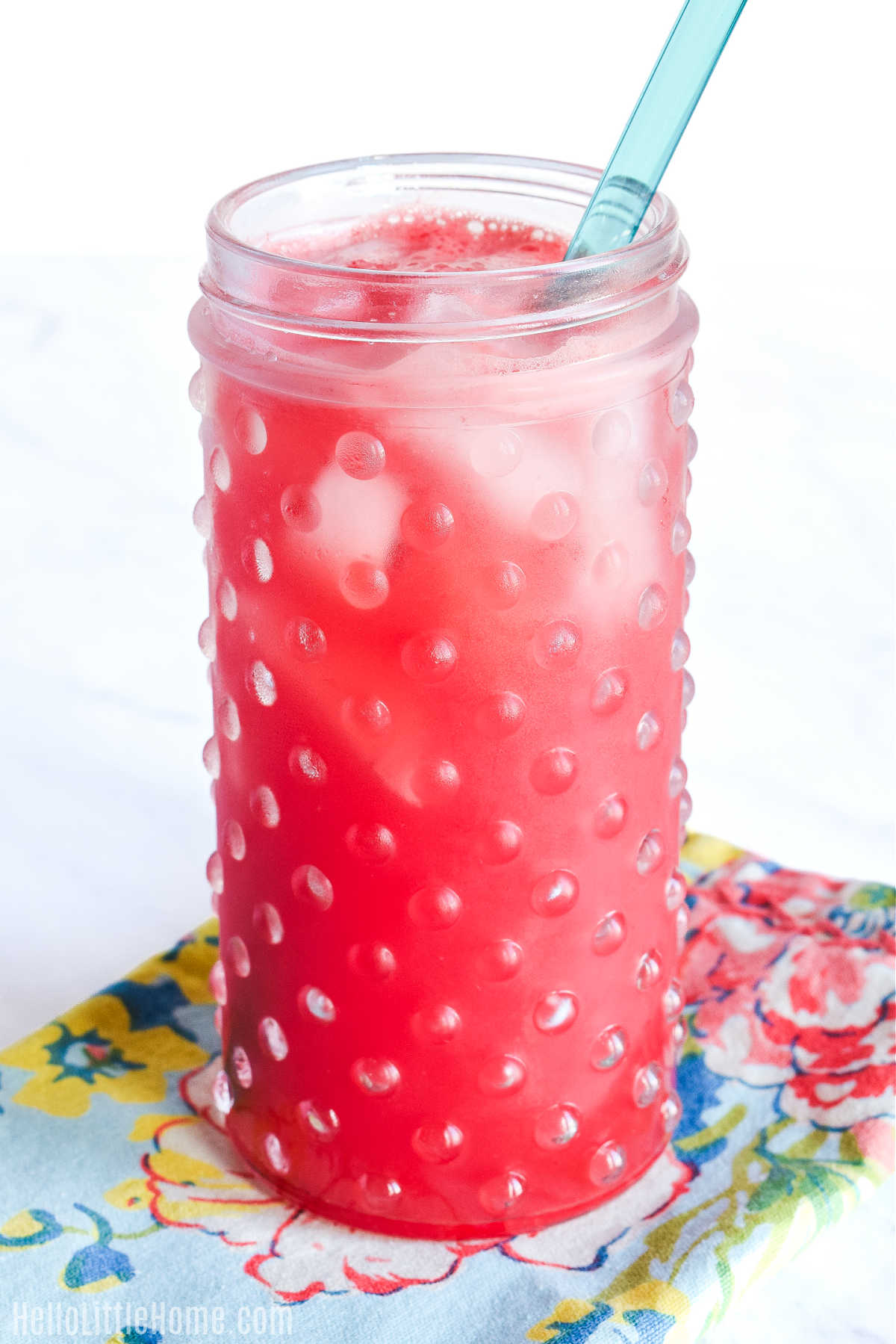 A Watermelon Agua Fresca served with a straw on a patterned napkin.
