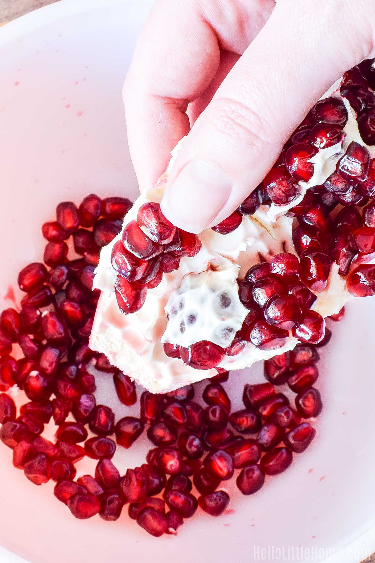 A hand removing the seeds from the fruit over a bowl.