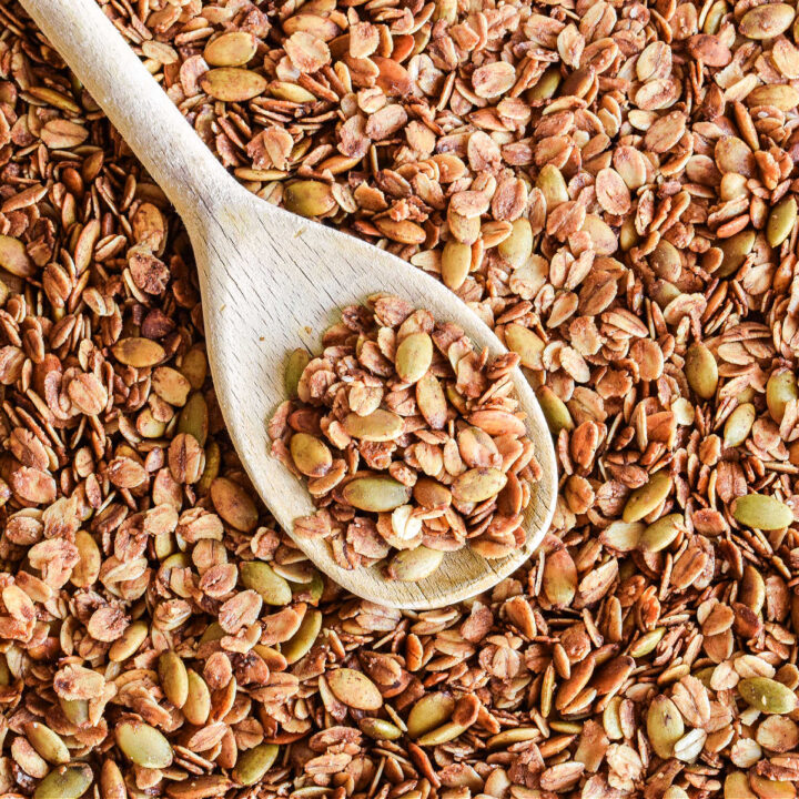 A pan of Pumpkin Seed Granola with a wood spoon in it.