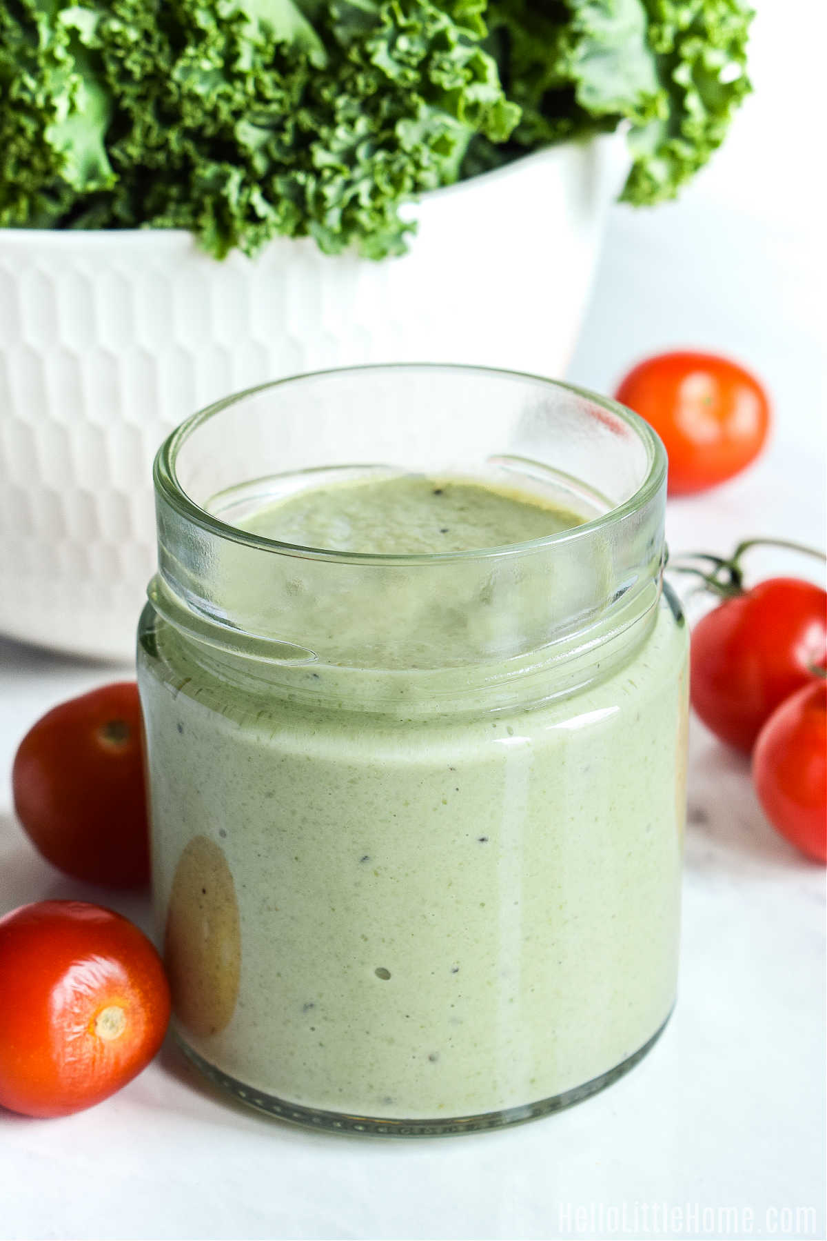Closeup of a jar of Pumpkin Seed Salad Dressing surrounded by cherry tomatoes.