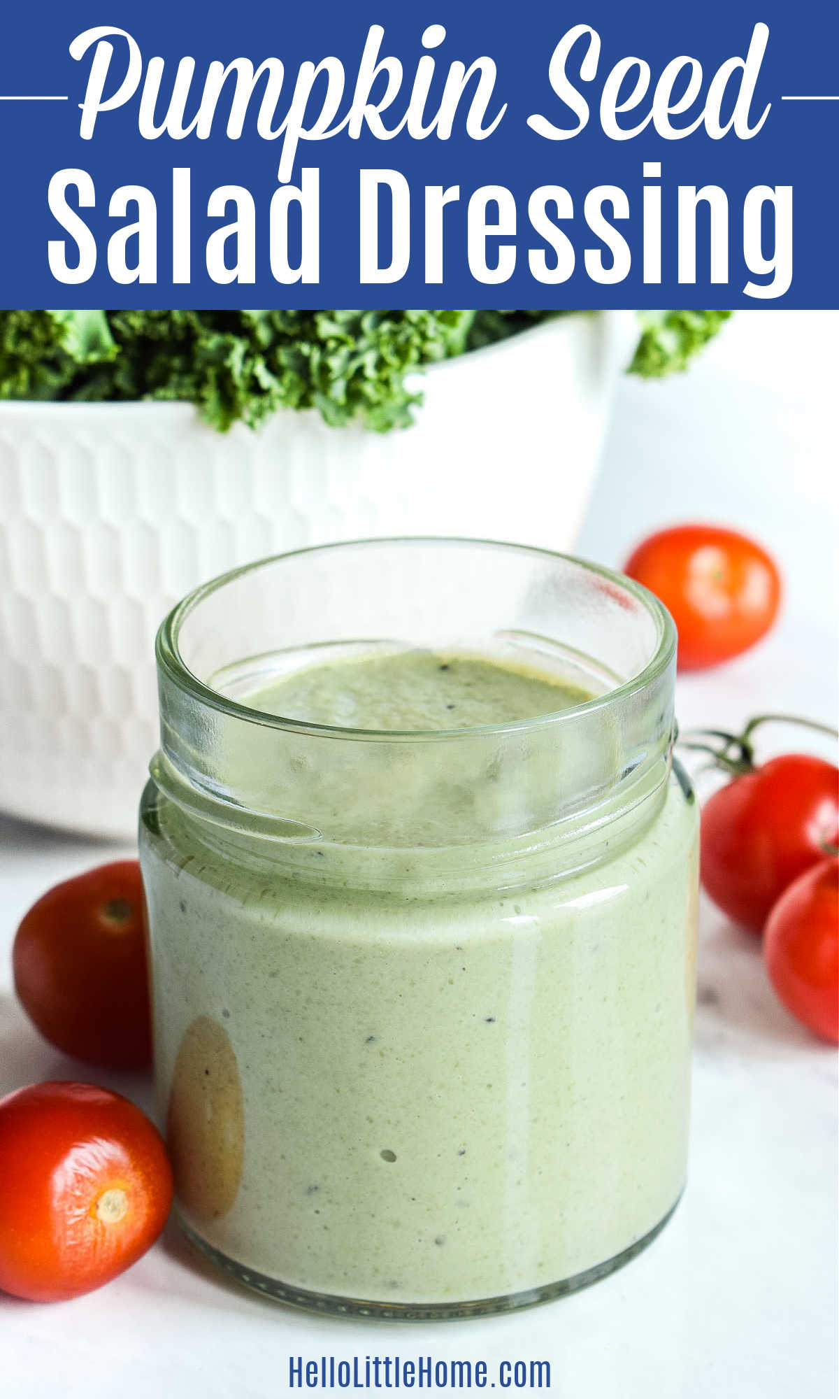 A jar of the finished Pumpkin Seed Salad Dressing surrounded by cherry tomatoes.