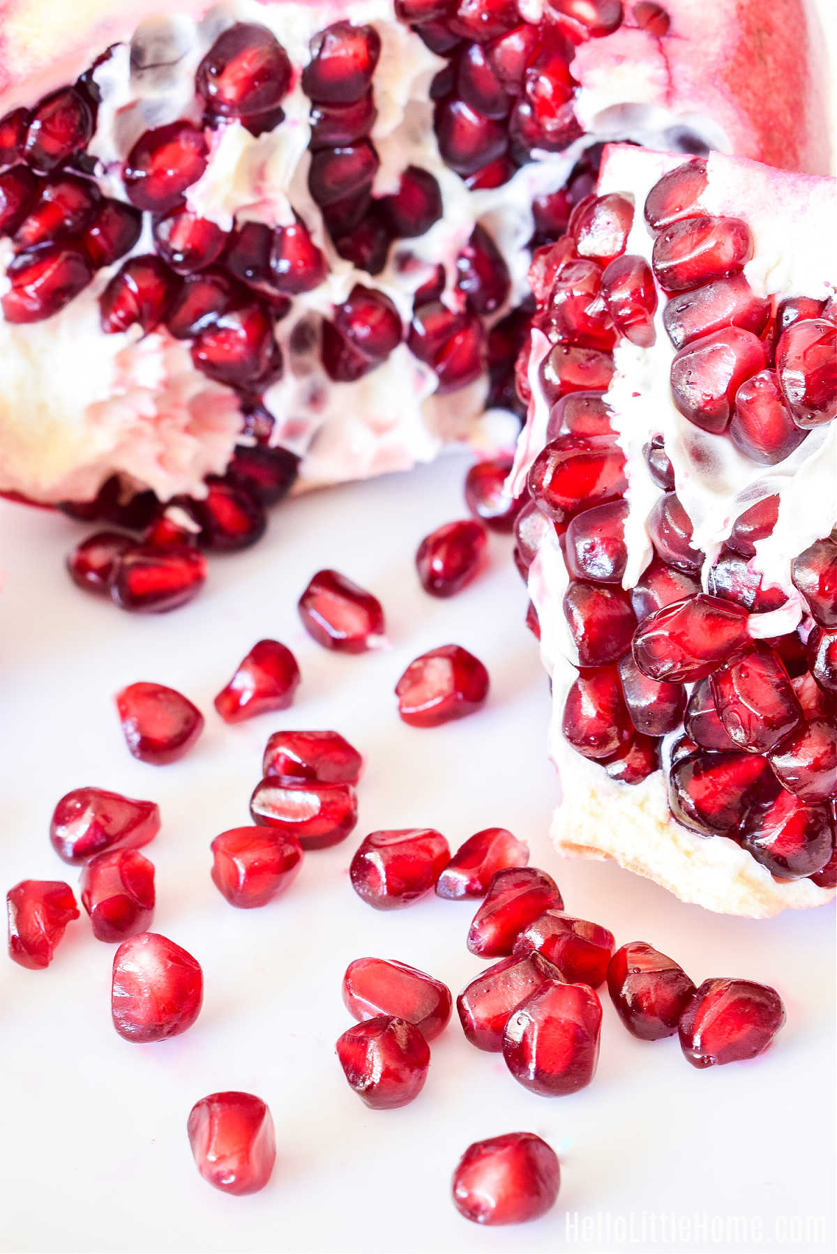 Closeup of pomegranate pieces and seeds on a white plate.