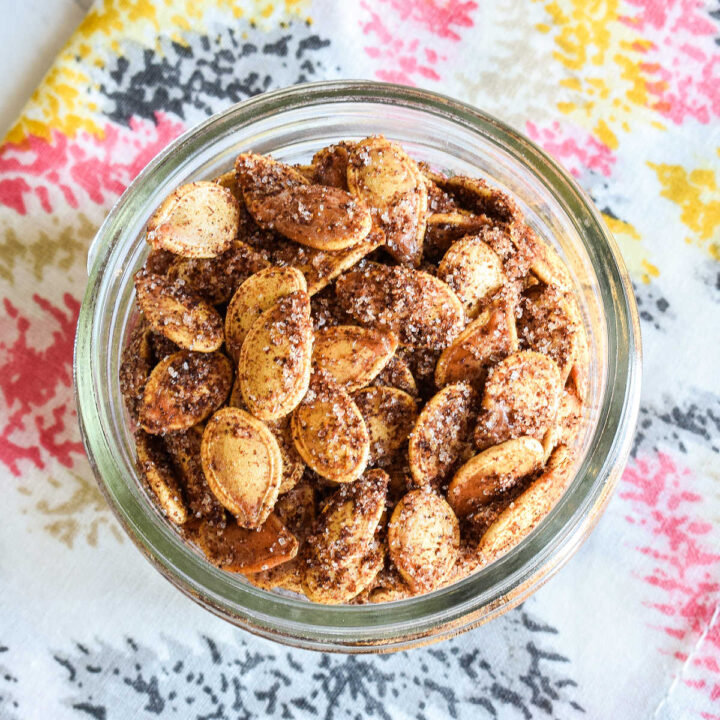 Sweet and Spicy Pumpkin Seeds served in a jar on a patterned napkin.