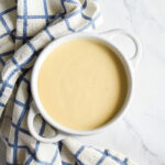 A bowl of Vegan Honey Mustard served next to a checked napkin.