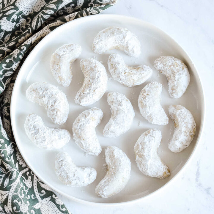 Almond Crescent Cookies served on a round tray next to a green napkin.