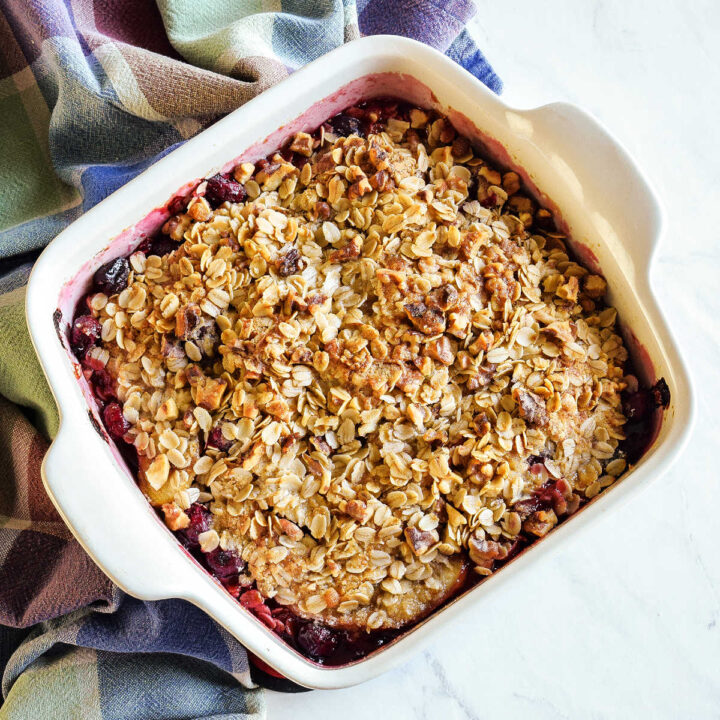 Apple Cranberry Crisp served in a baking dish next to a plaid napkin.