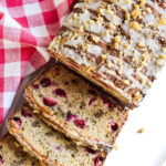 Cranberry Banana Bread served on a platter next to a checked napkin.