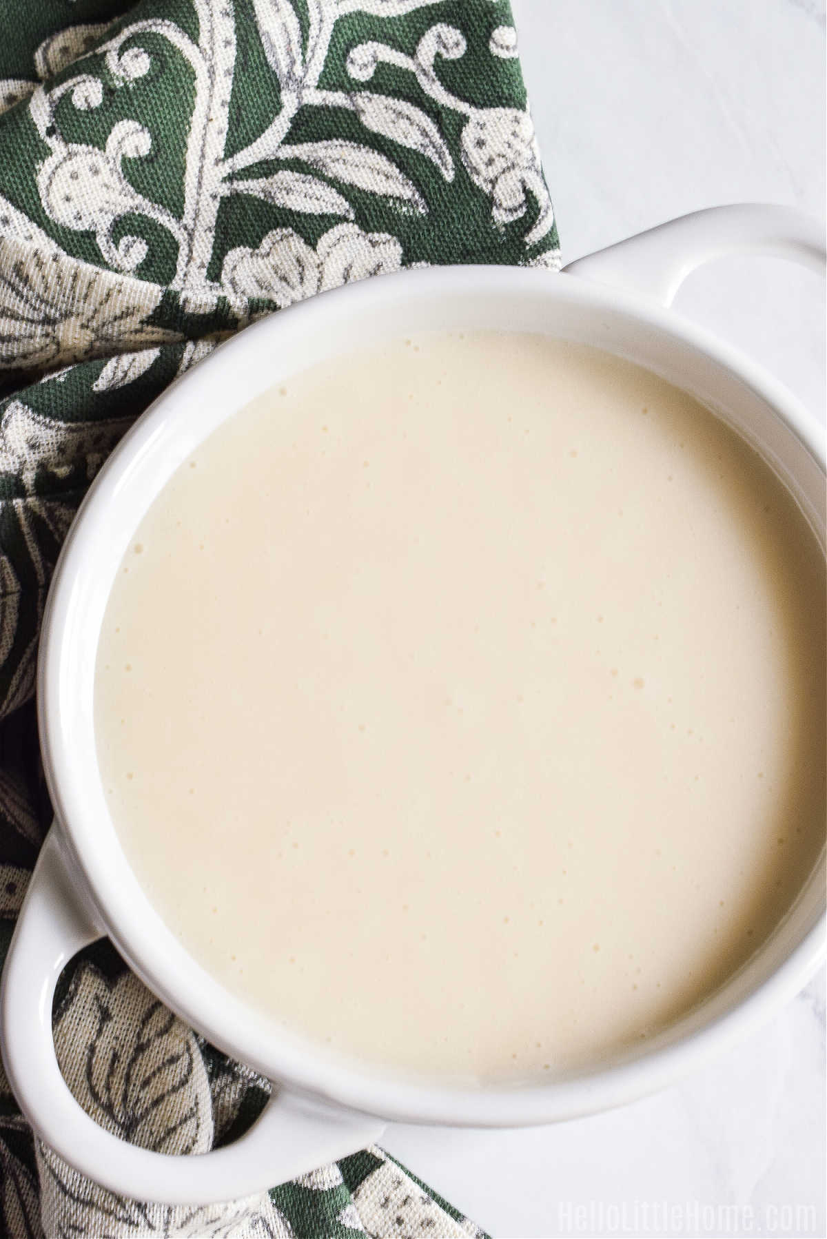 A bowl of homemade glaze served next to a patterned napkin.
