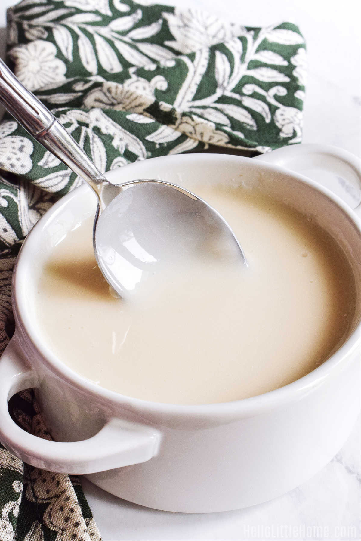 A spoon stirring a bowl of icing.