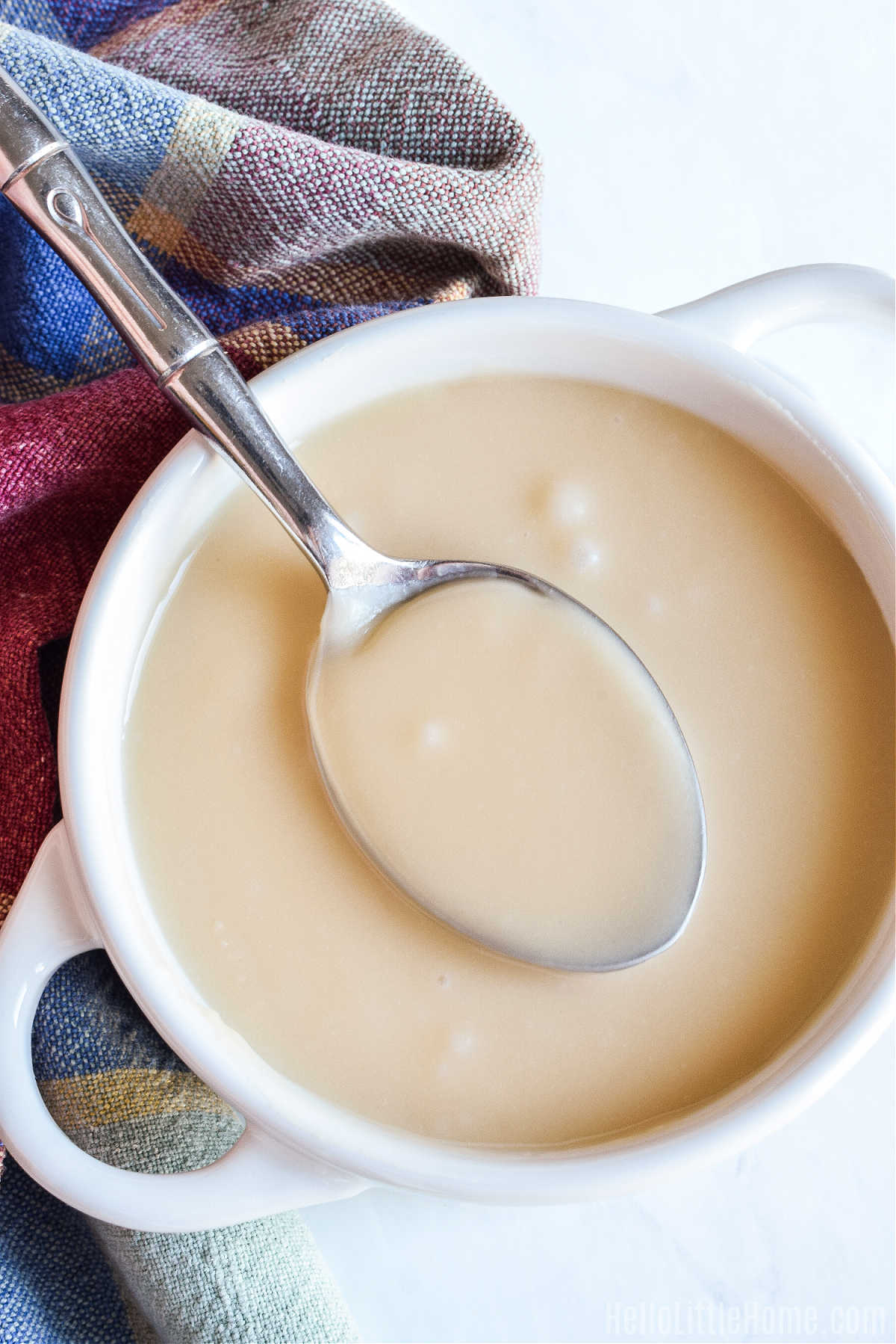 A spoonful of Maple Drizzle held over a bowl of the finished recipe.