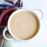 A bowl of Maple Glaze served next to a plaid napkin.