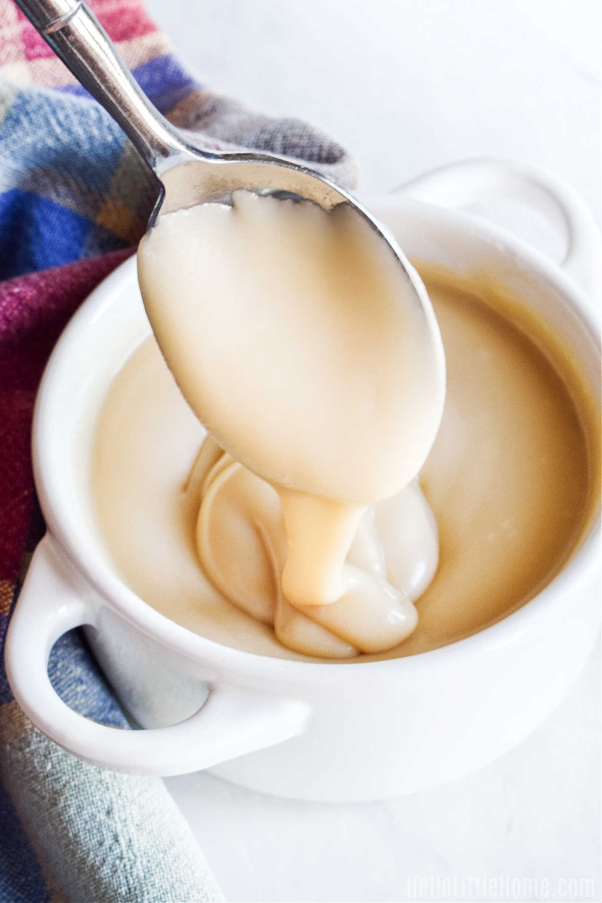 A spoon drizzling the homemade icing into a white bowl.