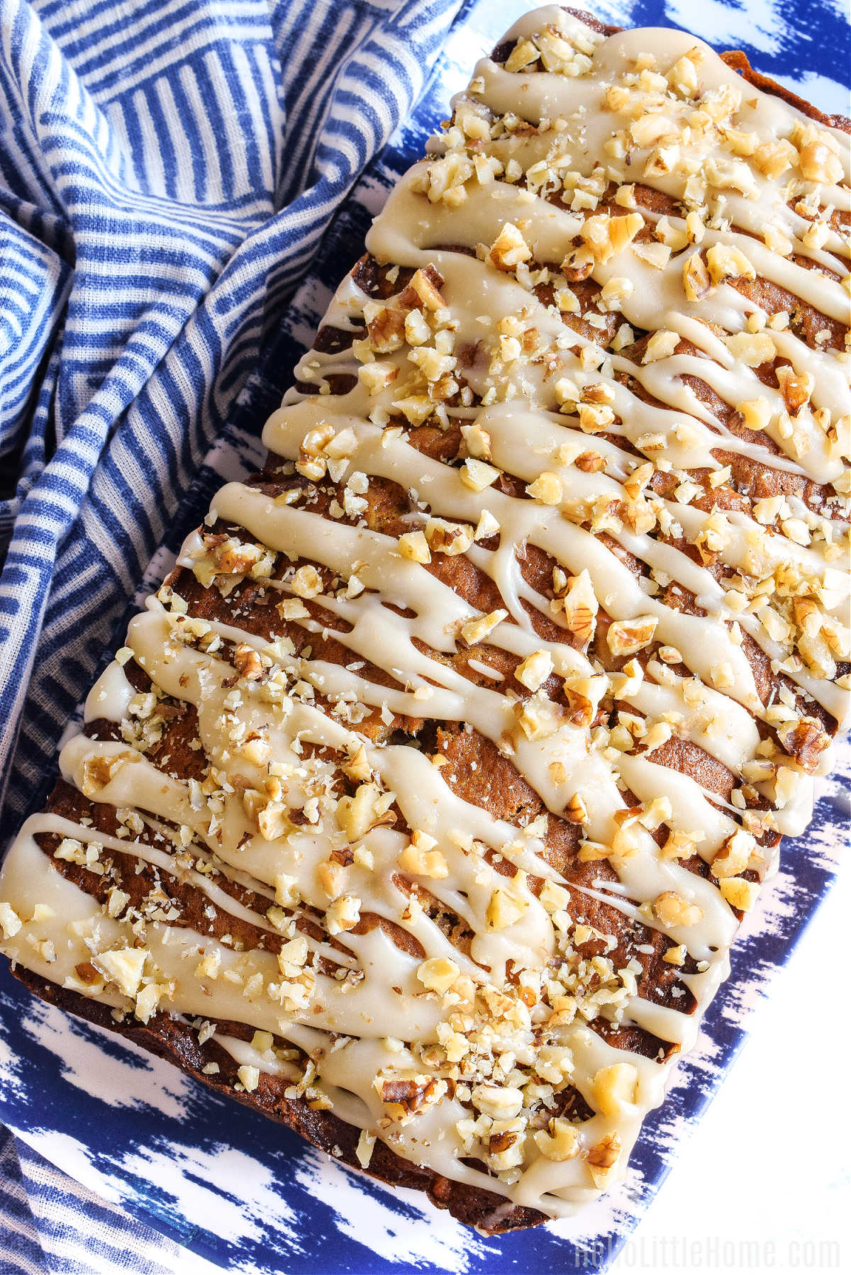 A loaf of bread drizzled with glaze and sprinkled with nuts.