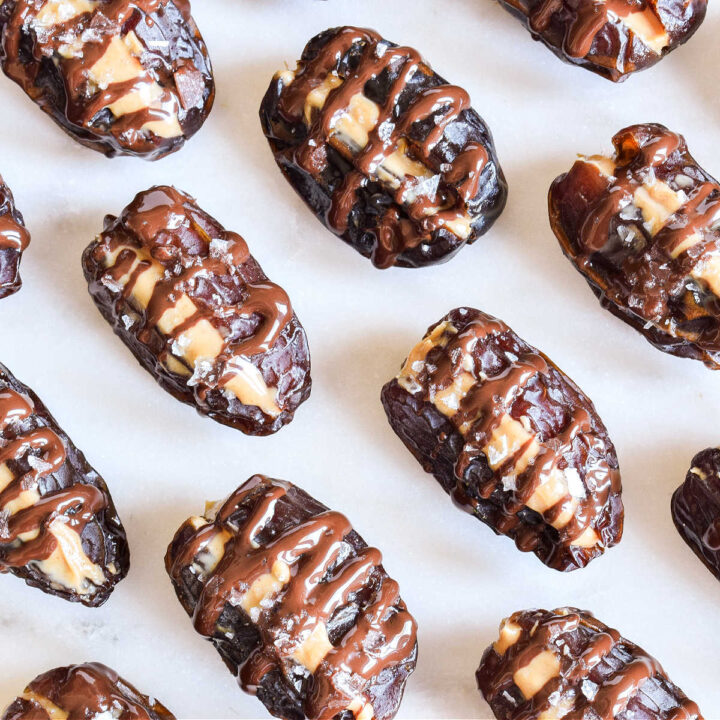 Peanut Butter Dates drizzled with Chocolate served on a marble tray.