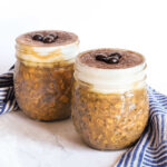 Two jars of Tiramisu Overnight Oats served with a napkin on a marble counter.