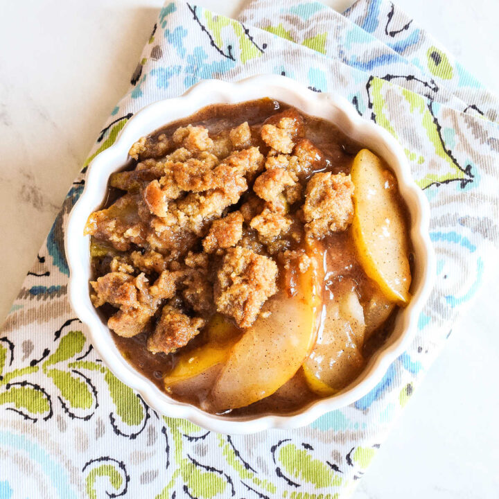 Pear Crumble served in a white bowl on a patterned napkin.
