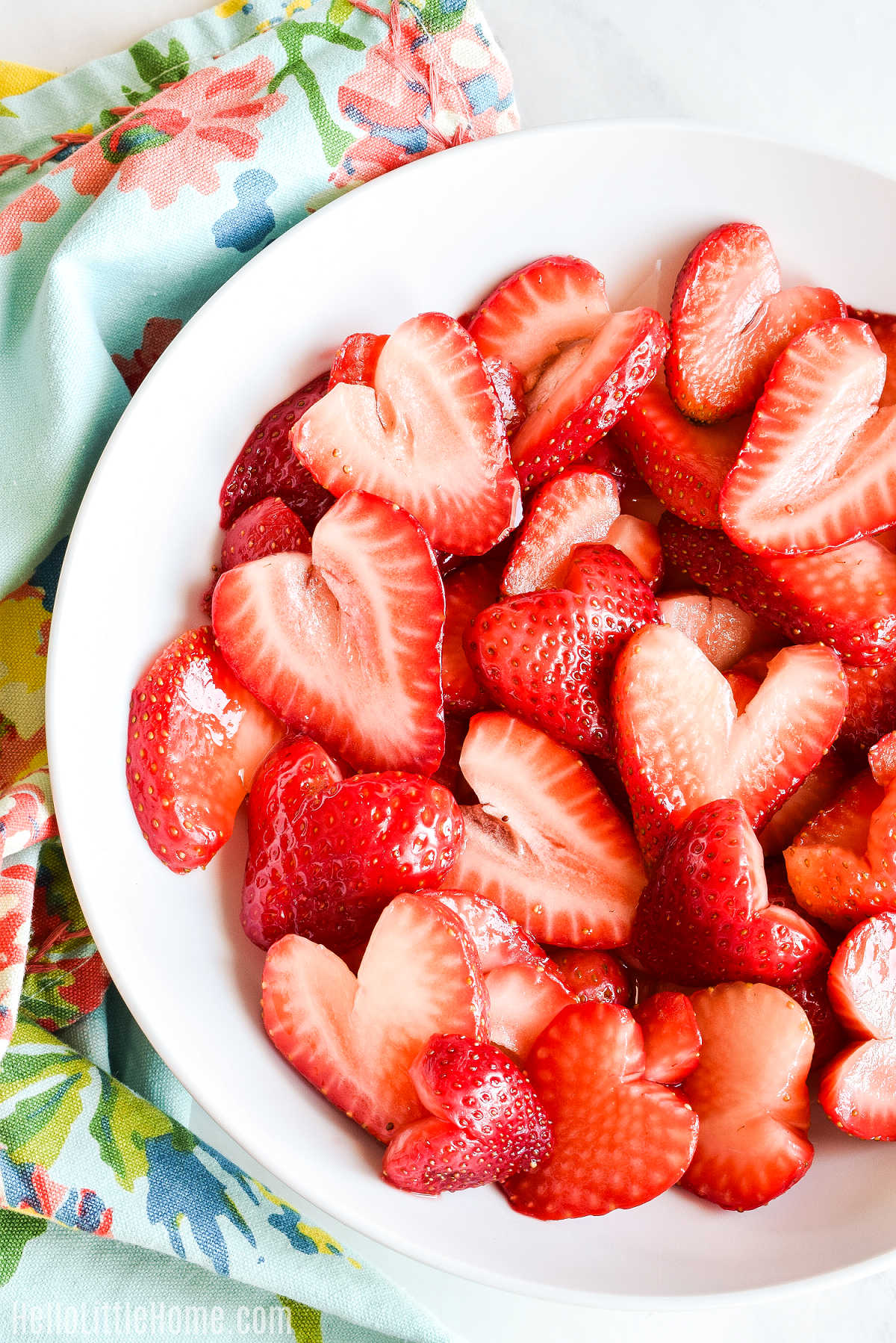Macerated Strawberries served in a white bowl next to a patterned napkin.