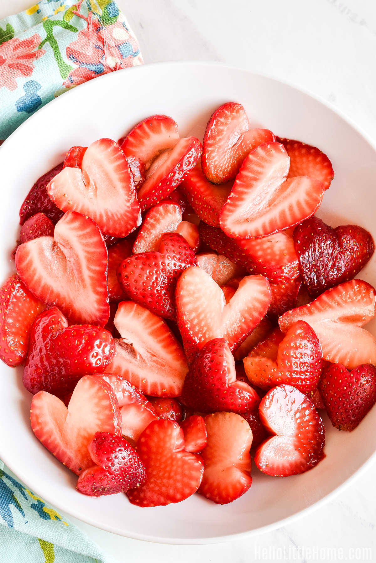 A bowl of sugared strawberries served on a marble counter with a napkin.
