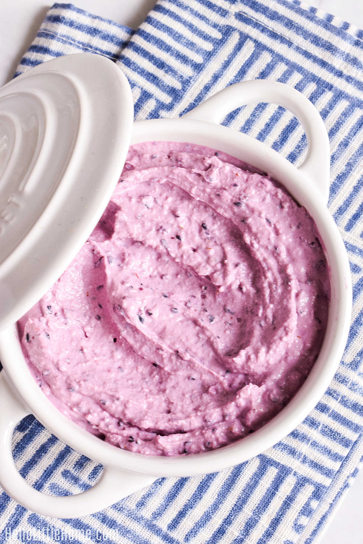 Homemade Blueberry Cream Cheese served in a white crock on a striped napkin.