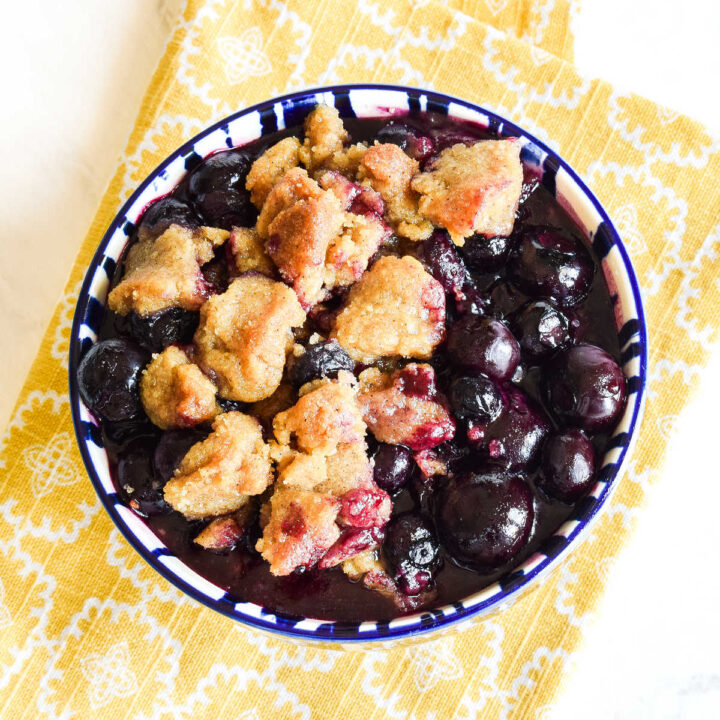 Homemade Blueberry Crumble served in a bowl on a yellow napkin.