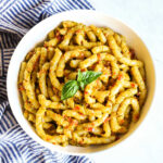 A bowl of Busiate alla Trapanese served with a striped napkin.