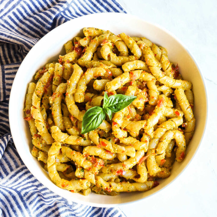 A bowl of Busiate alla Trapanese served with a striped napkin.