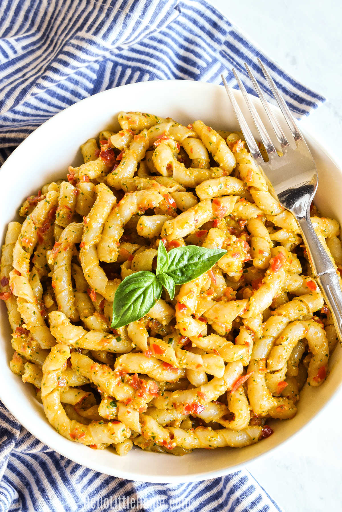 Busiate alla Trapanese served in a bowl with a fork resting on the edge.