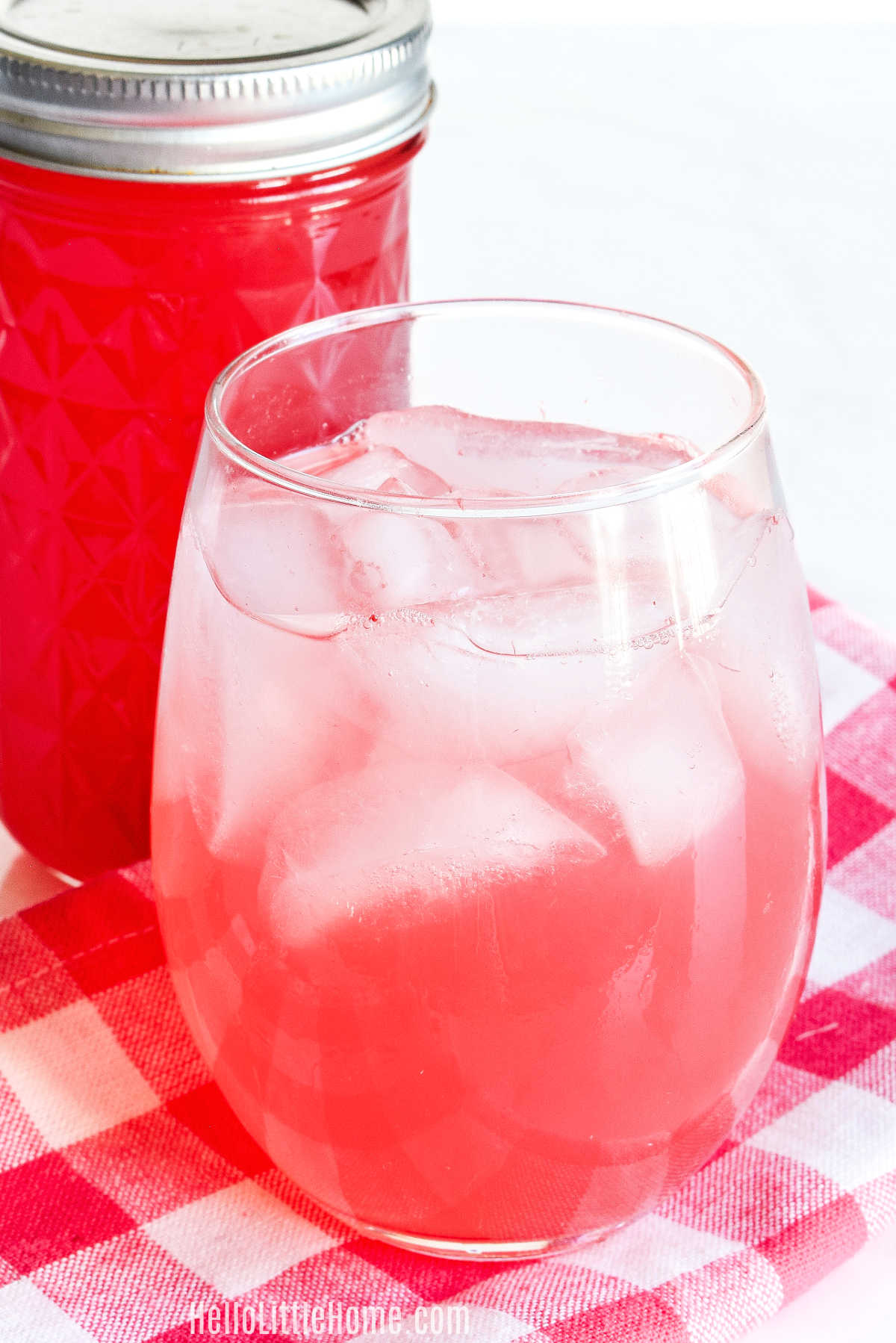 A drink made with the simple syrup with a jar of syrup behind it.