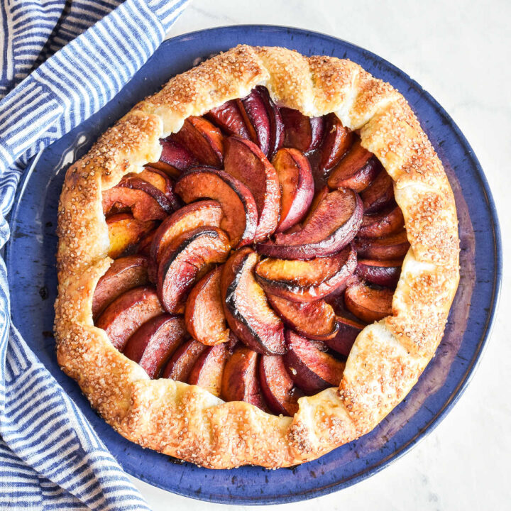 A Peach Galette served on a blue plate next to a striped napkin.