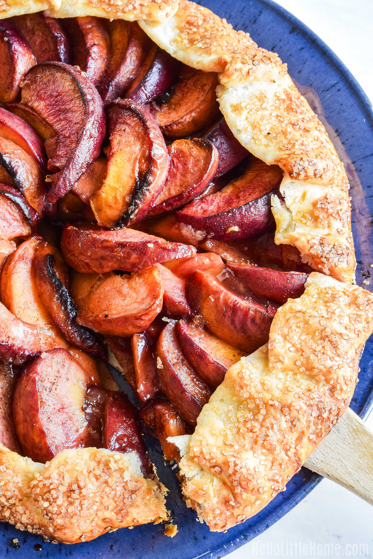 A Peach Galette with a slice being removed with a wood spatula.